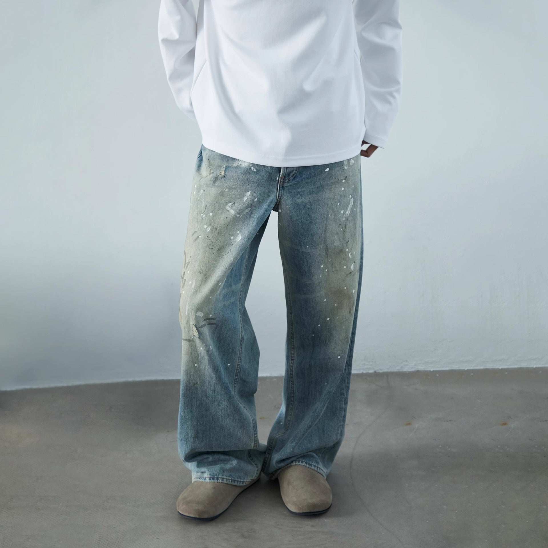 Calça jeans neutra de perna larga com estampa desgastada de respingos de tinta.